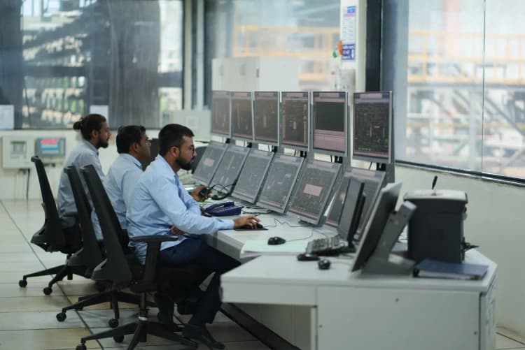 Aarti Industries plant workers examining industrial valve while wearing hard hats and gloves
